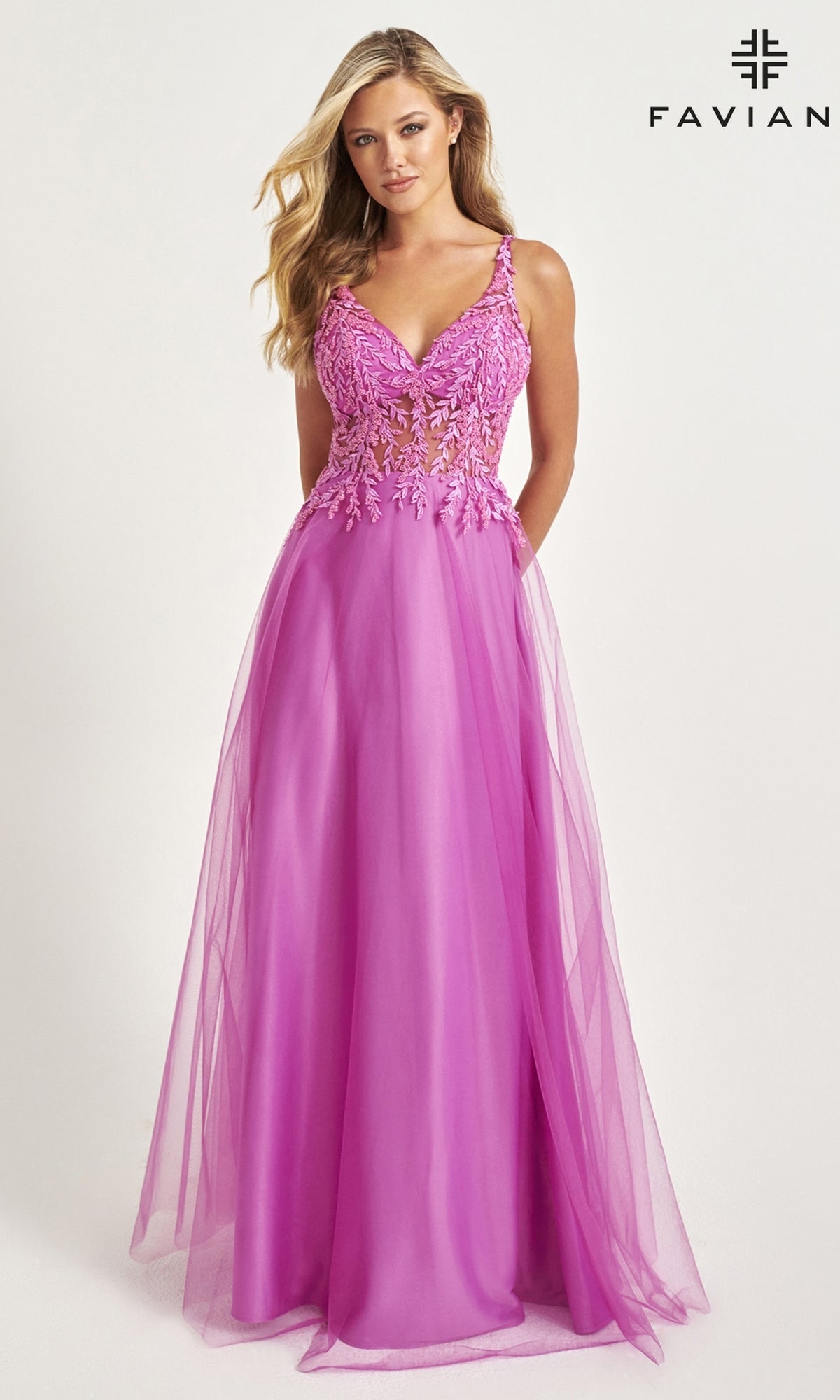 Woman in a Faviana Sheer-Bodice Long Tulle Prom Dress 11055, featuring a sleeveless pink design with floral lace bodice details and a floor-length tulle skirt, standing against a light background.
